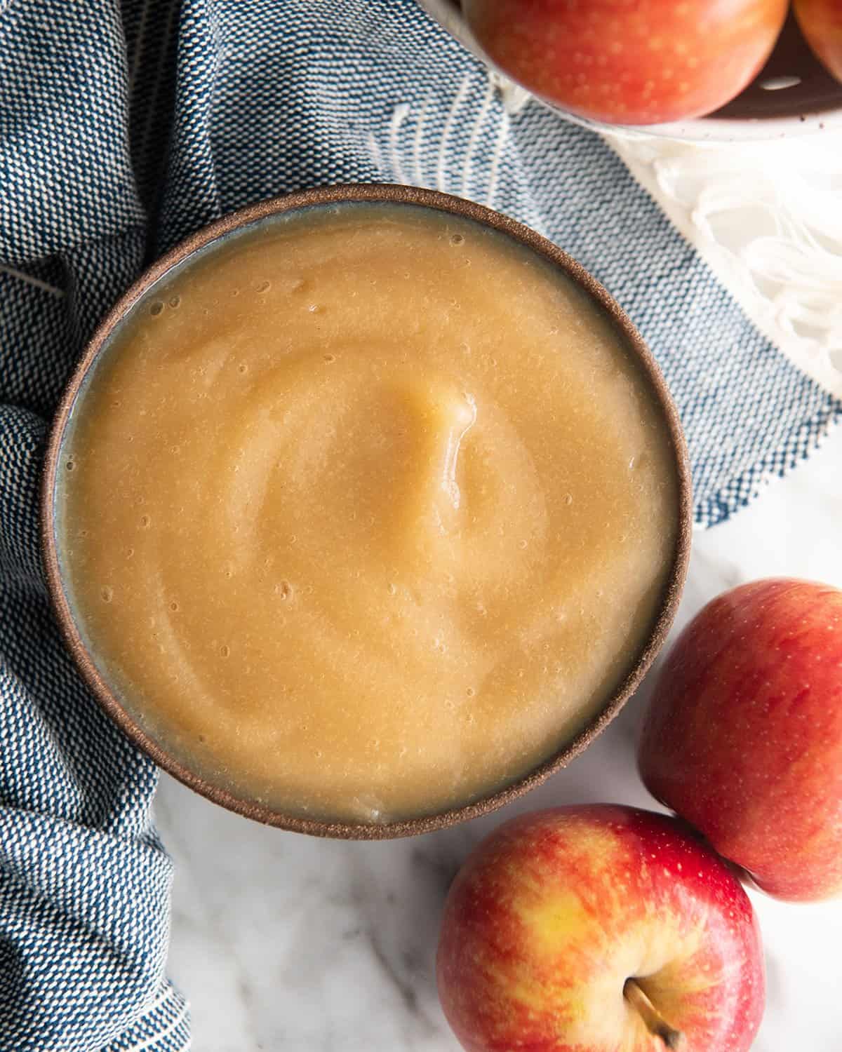 a bowl of homemade applesauce with apples around it