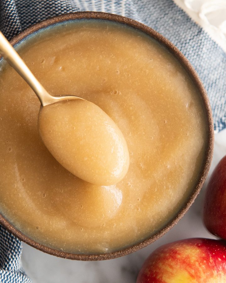 a spoon taking a scoop of homemade applesauce out of a bowl