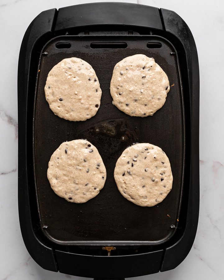 chocolate chip pancakes cooking on a griddle