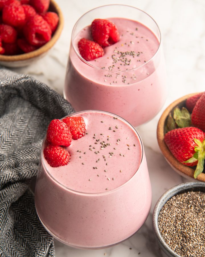 two glasses of Protein Smoothie Recipe with chia seeds and raspberries on top