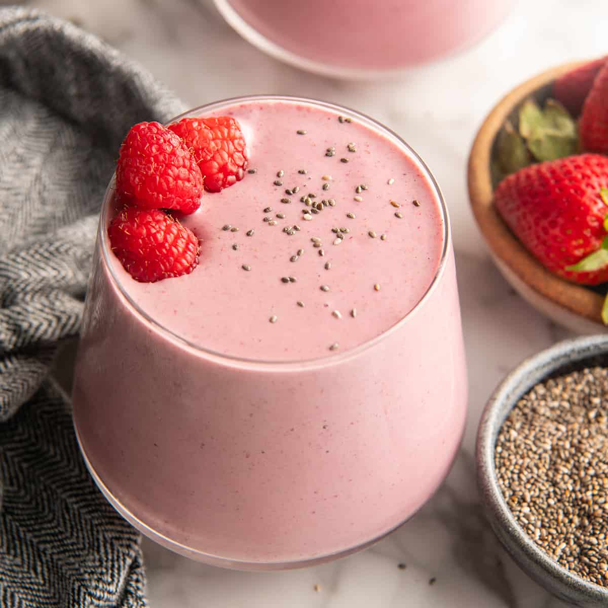 a glass of Protein Smoothie Recipe with chia seeds and raspberries on top