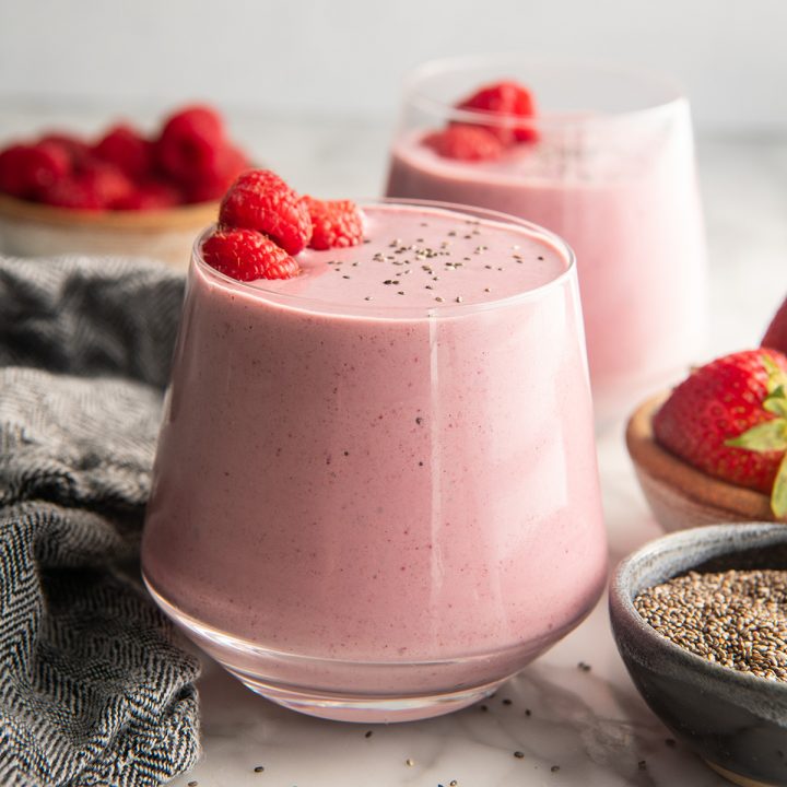 two glasses of Protein Smoothie with raspberries and chia seeds on top