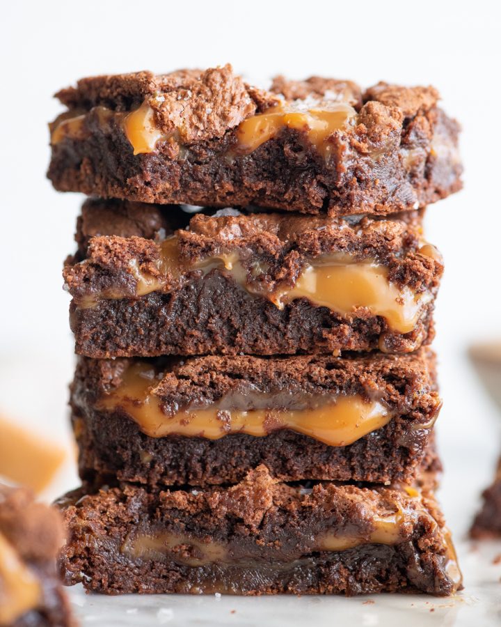 a stack of 4 salted caramel brownies, the top one with a bite taken out of it. 