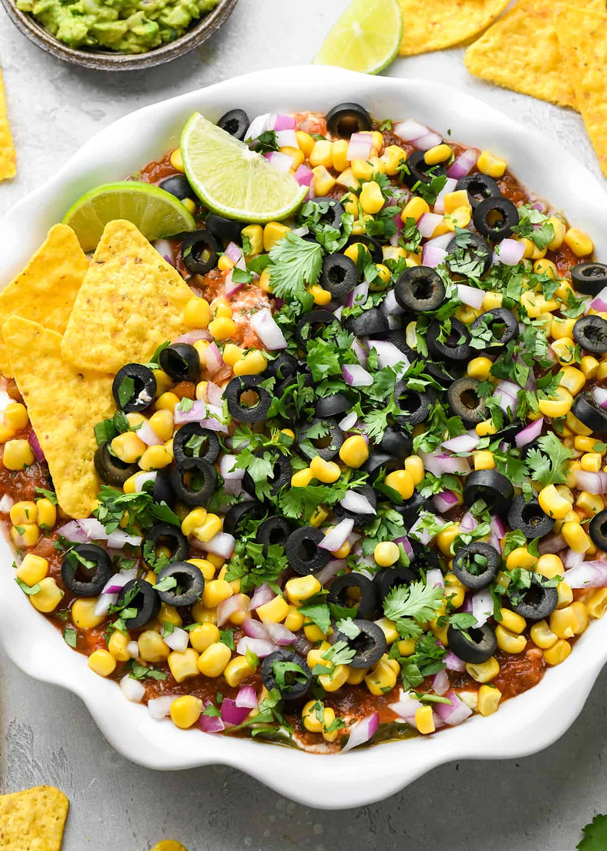Mexican 7 Layer Dip in a pie dish with chips