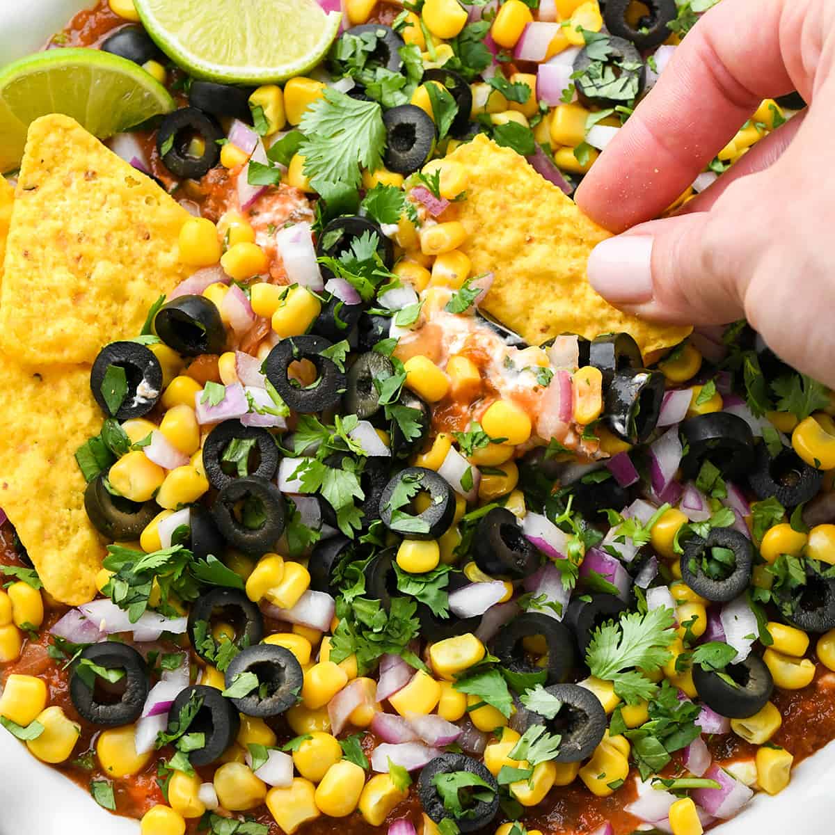 a chip dipping into Mexican 7 Layer Dip