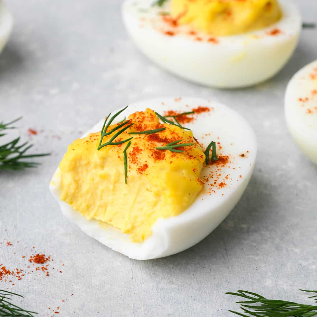 a deviled egg with a bite taken out of it garnished with dill and paprika