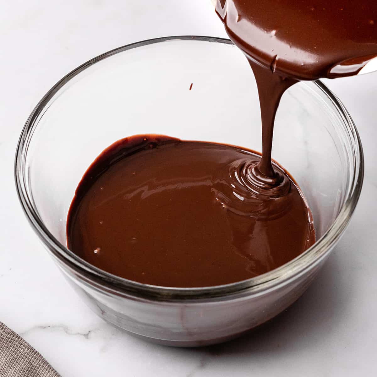 chocolate ganache being poured into a glass bowl