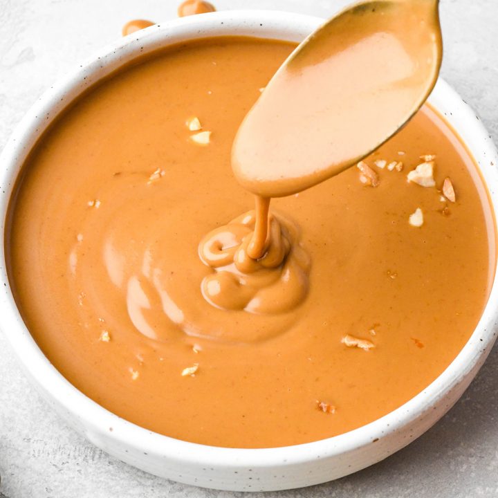 a spoon drizzling peanut sauce into a bowl