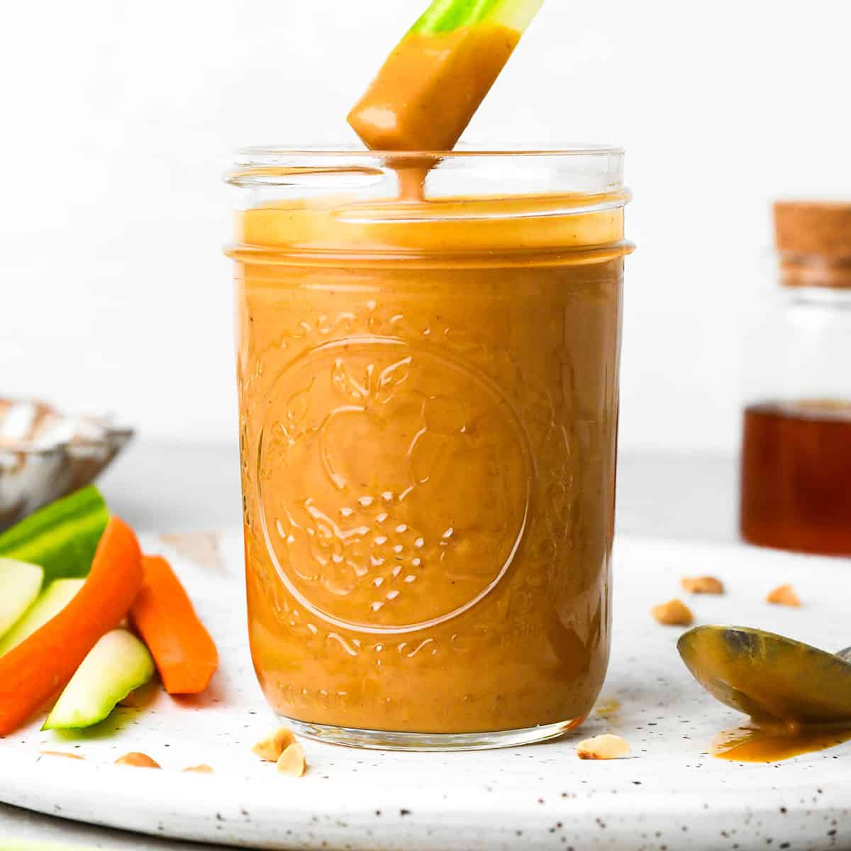 celery being dipped into a jar of peanut sauce