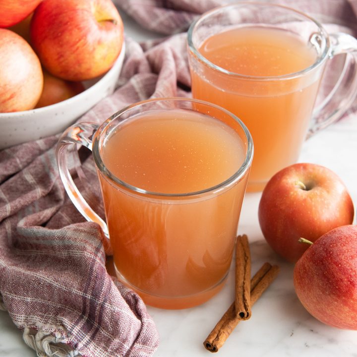 two glass mugs filled with homemade apple cider