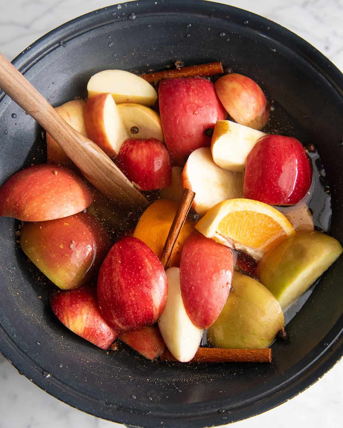 how to make apple cider recipe - a wooden spoon stirring the ingredients in the crock pot 