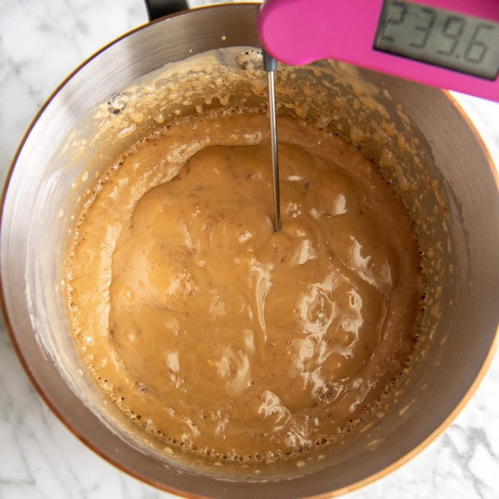 a thermometer in a pot of homemade caramel in its final stages of cooking