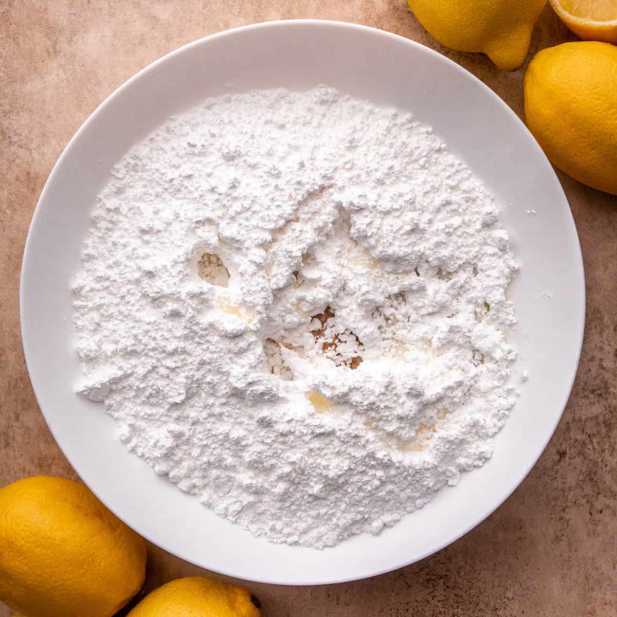 adding vanilla and milk and lemon juice to powdered sugar to make lemon glaze