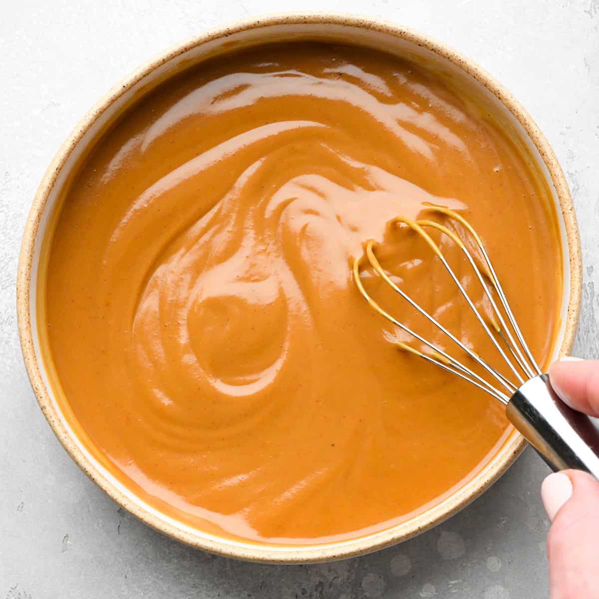 how to make peanut sauce - ingredients in a bowl being whisked
