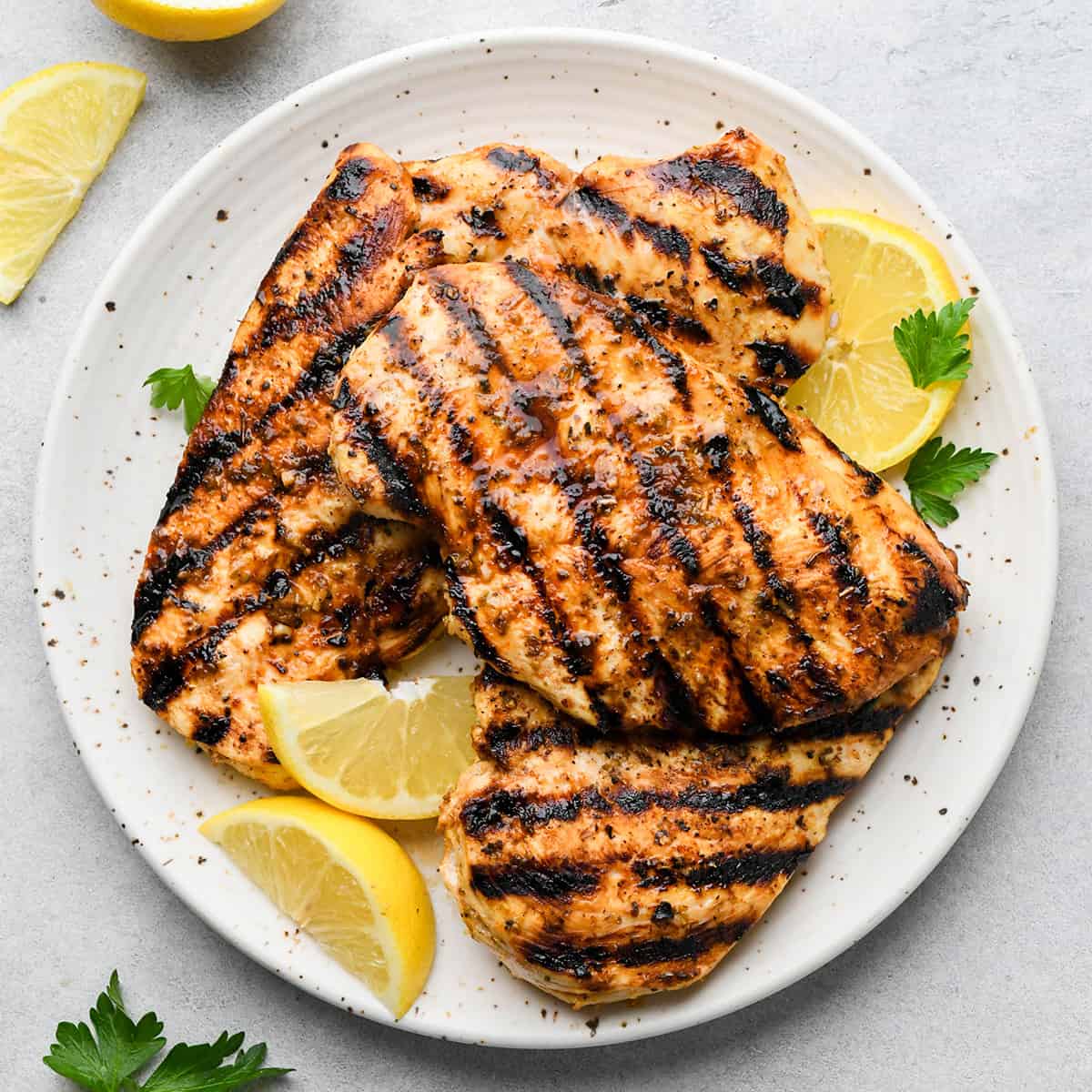 4 Greek chicken breasts on a plate with lemon