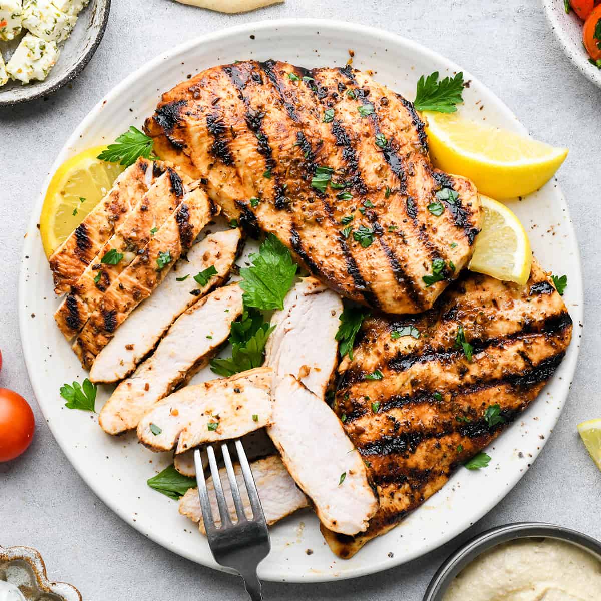 a plate of 3 Greek Chicken breasts, one sliced into strips