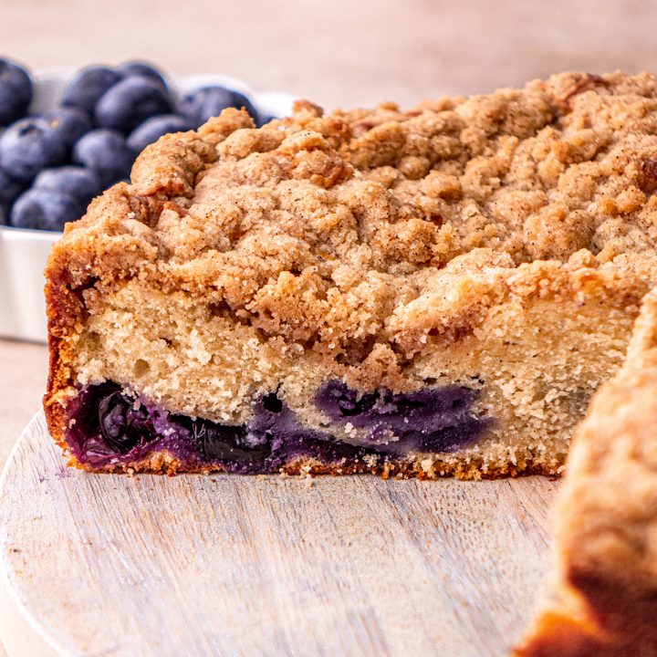 Blueberry Coffee Cake with a slice cut out of it so you can see the inside of a piece of cake