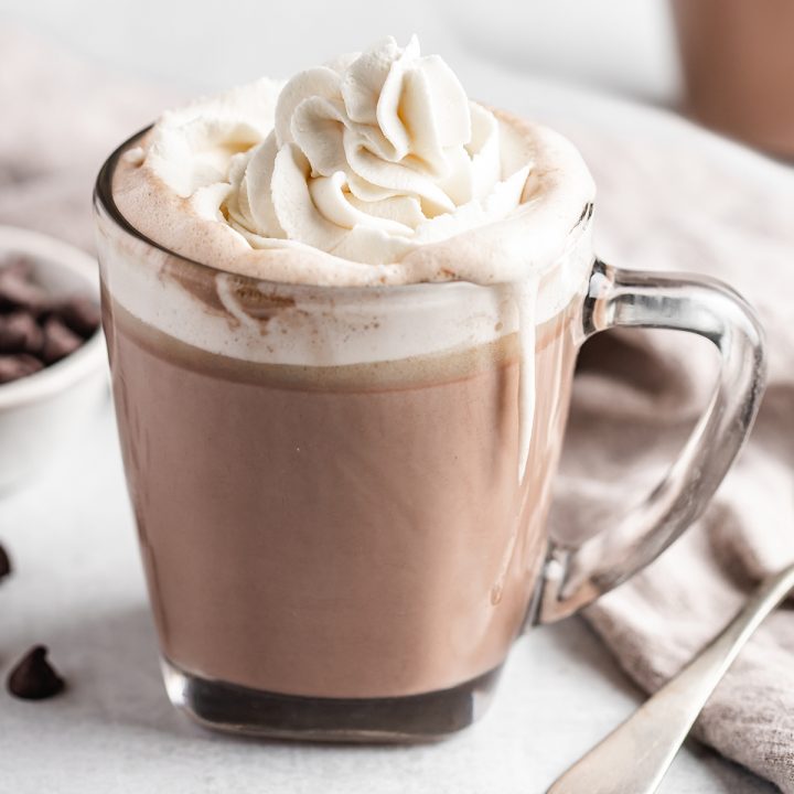 a glass mug full of Crockpot Hot Chocolate topped with whipped cream