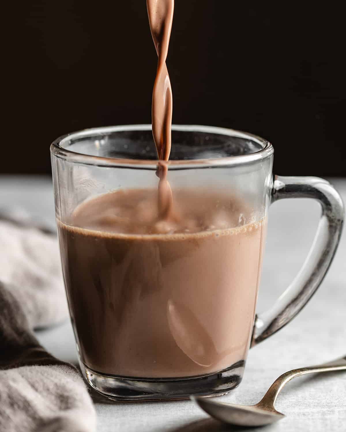 Crockpot Hot Chocolate being poured into a glass mug