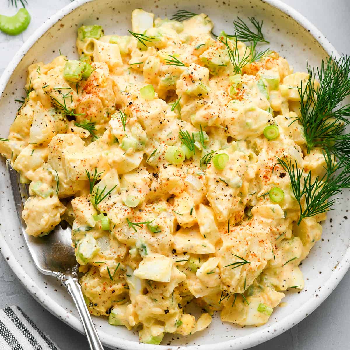 potato salad on a plate with a fork garnished with dill and green onions