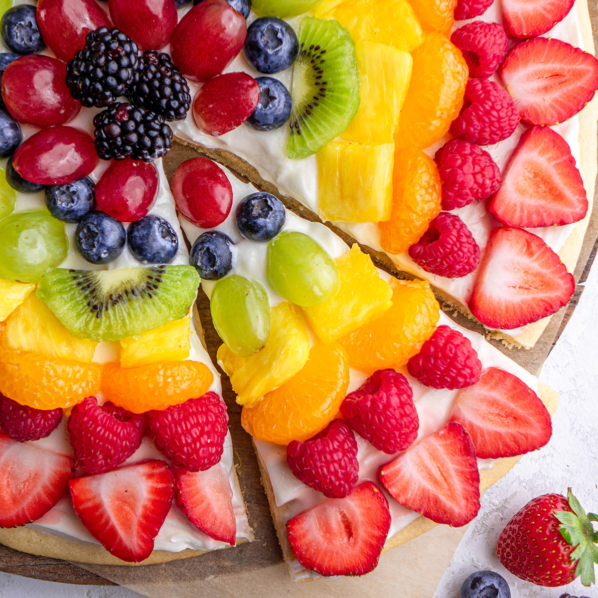 fruit pizza with a triangular slice cut out of it
