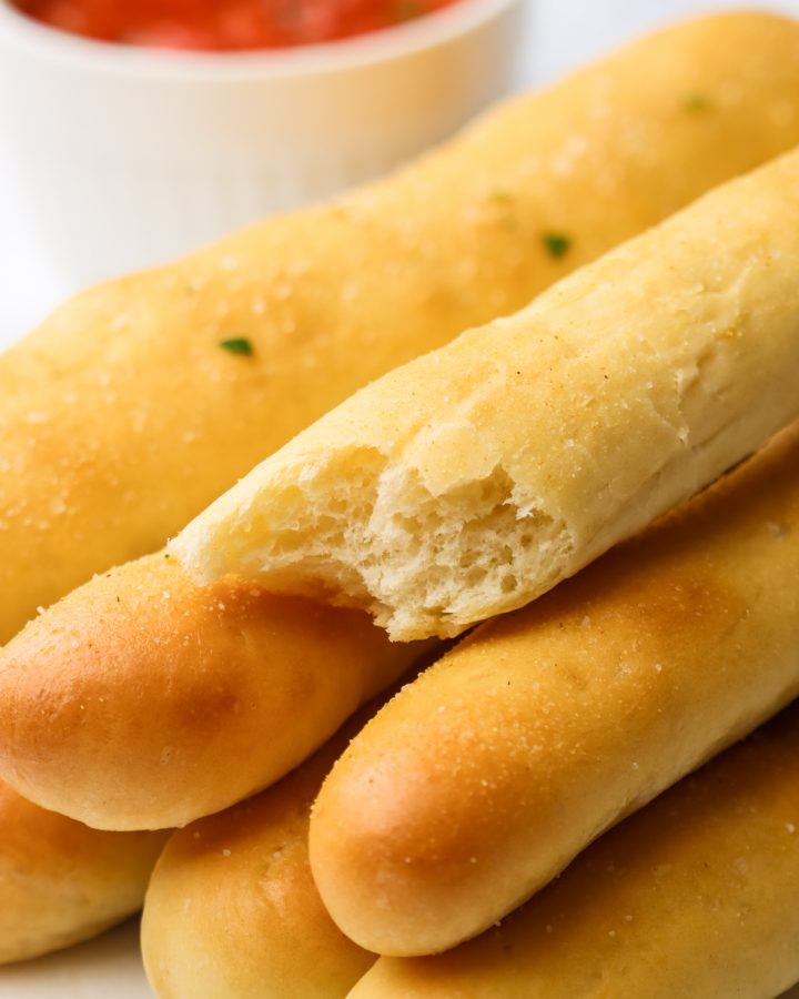 a stack of breadsticks, one with a bite taken out of it