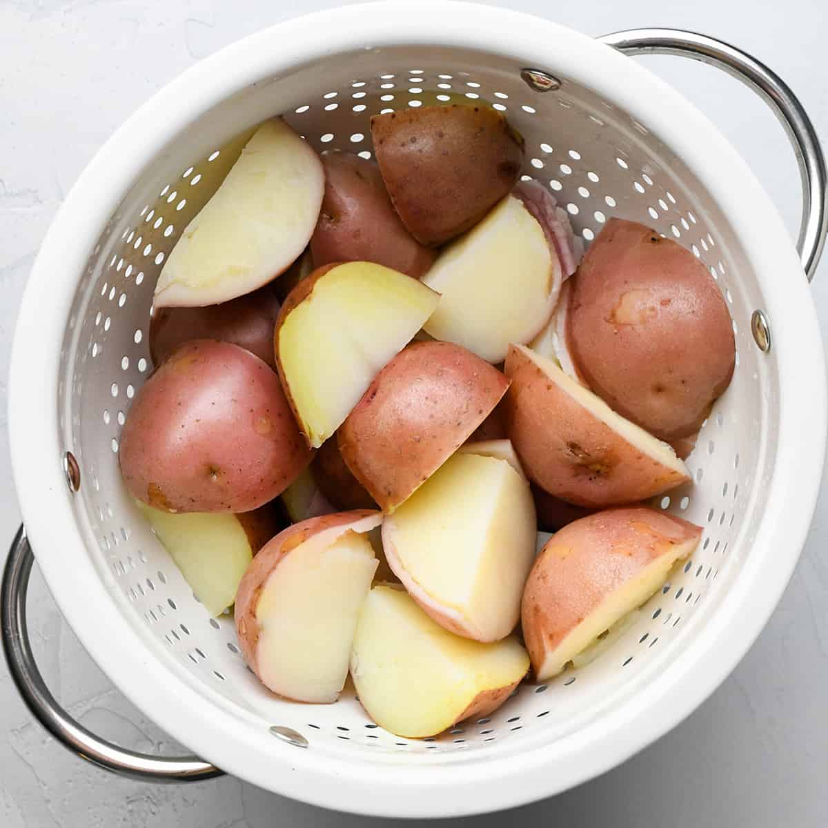 draining boiled potatoes in a colander to make potato salad