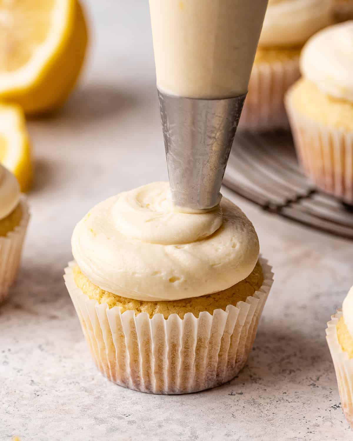 Lemon Buttercream Frosting being piped on top of a cupcake with a pastry bag