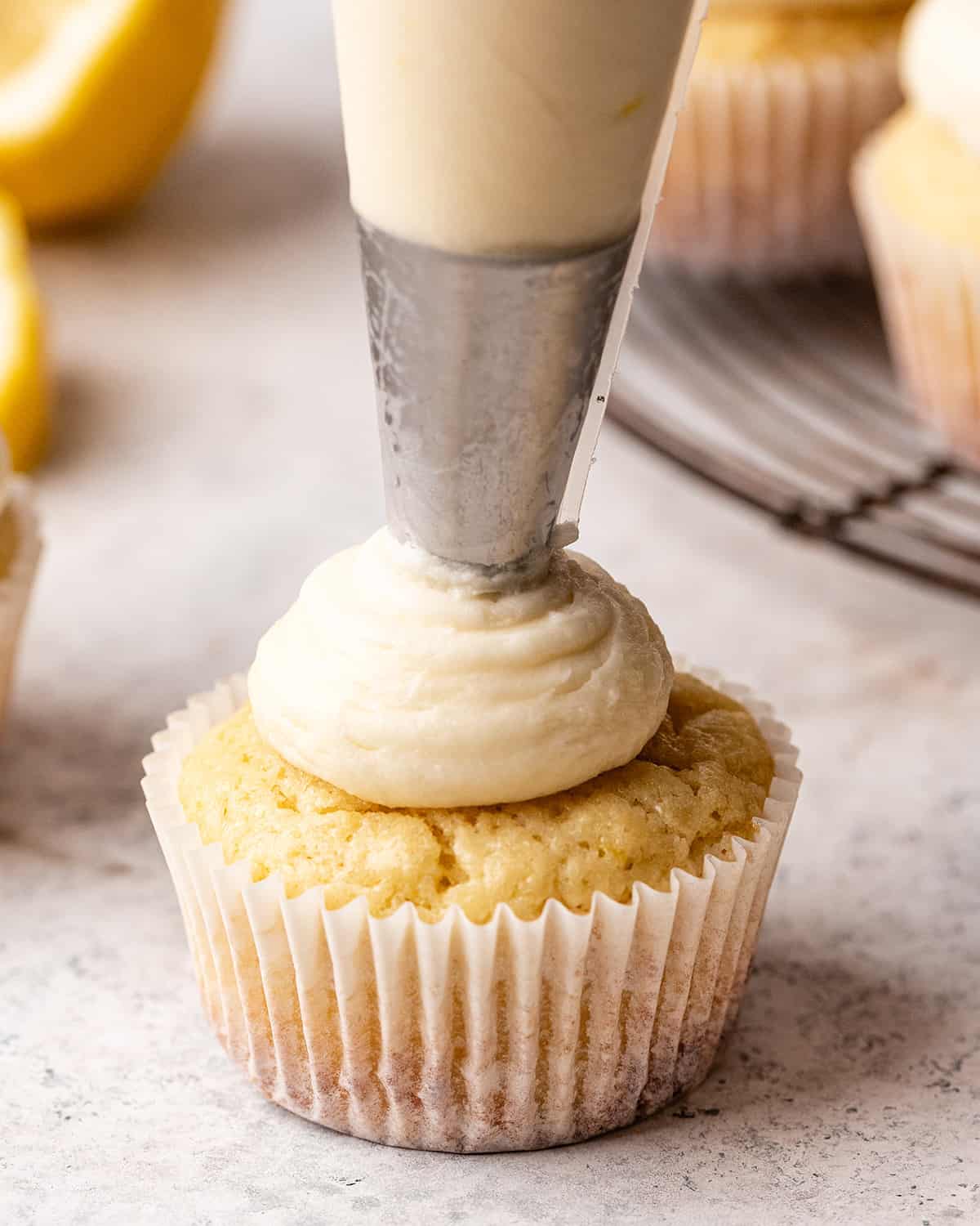 lemon buttercream frosting being piped onto a cupcake