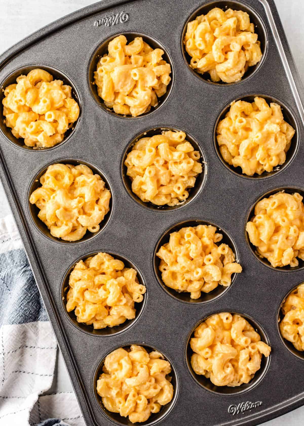 making macaroni and cheese cups - mac and cheese mixture filling all 12 wells of a standard muffin tin