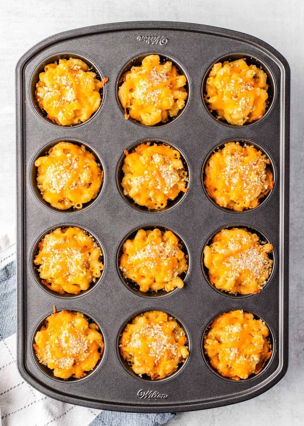 baked mac and cheese cups in a gray, 12-cup muffin pan after baking