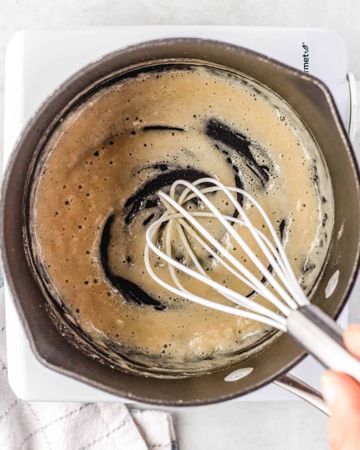 making mac and cheese cups - flour and butter mixture being whisked in a cast iron skillet