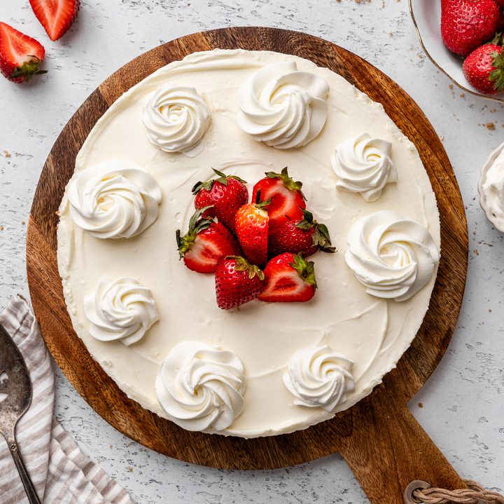 overhead view of a No Bake Cheesecake Recipe on a serving board with whipped cream and strawberries