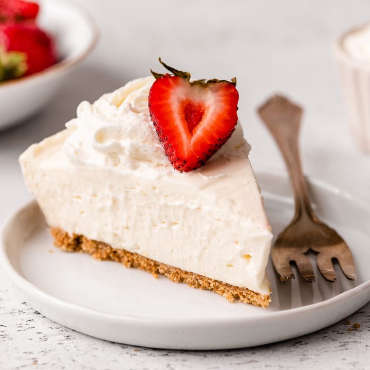 a slice of No Bake Cheesecake on a plate with whipped cream and a strawberry