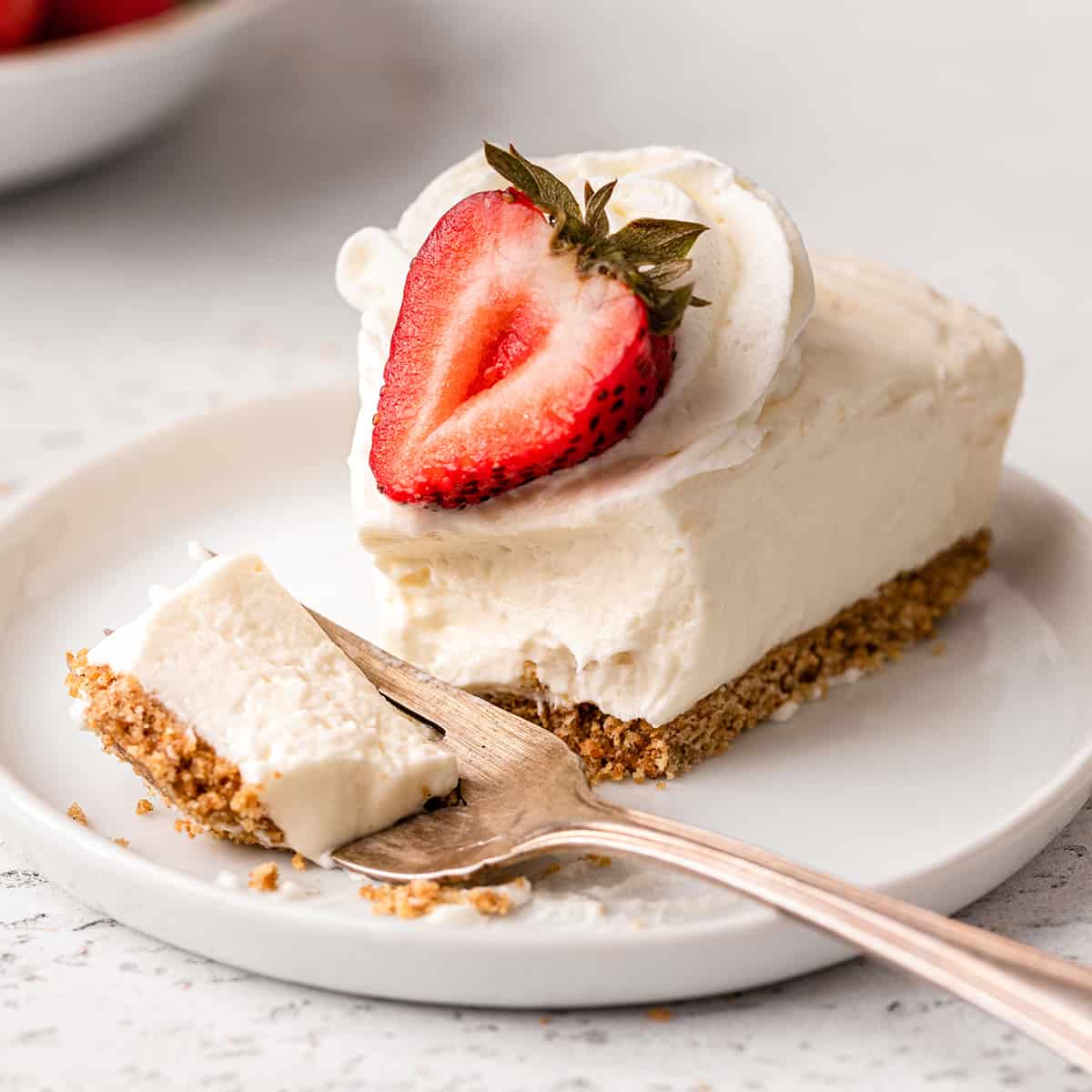 a fork taking a bite of a piece of No Bake Cheesecake on a plate