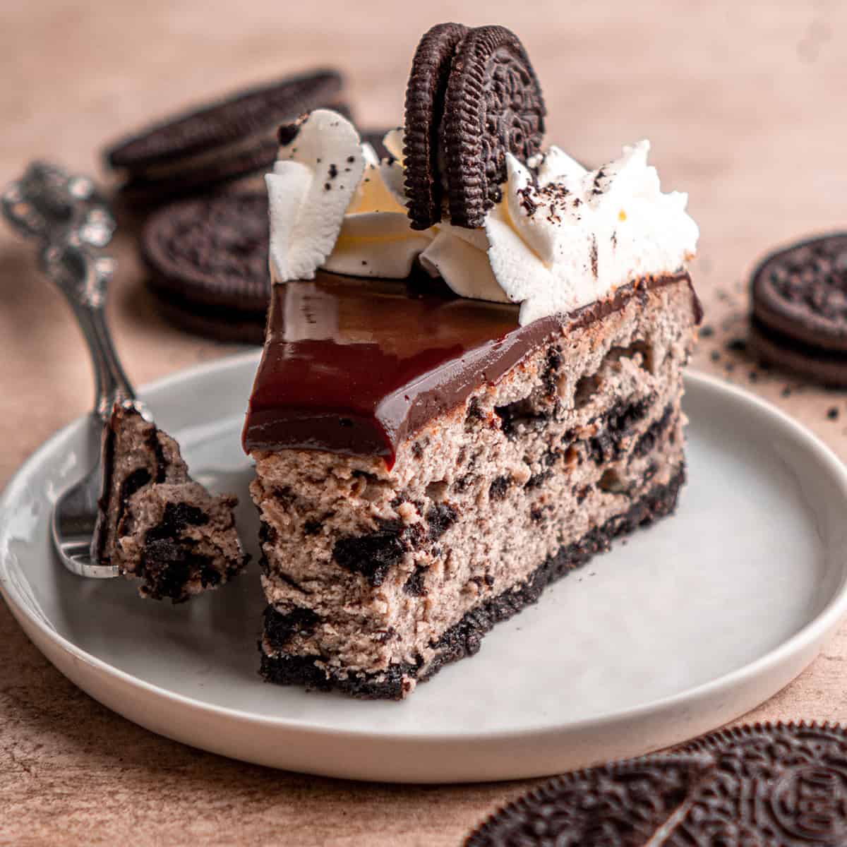 a slice of Oreo Cheesecake on a plate with a bite taken out of it