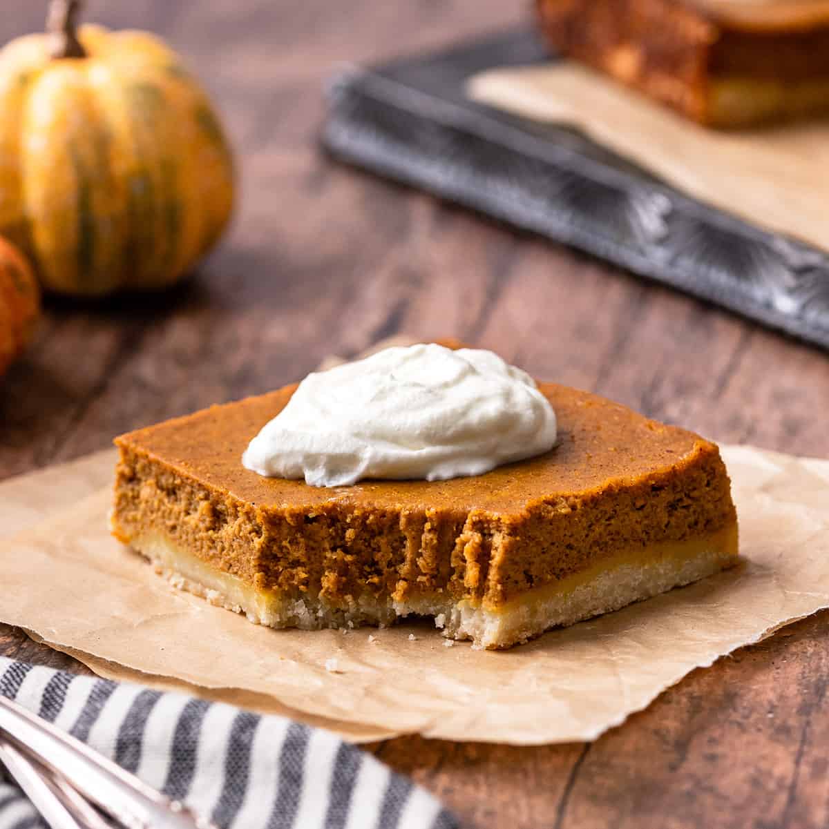 a Pumpkin Pie Bar with a bite taken out of it topped with whipped cream