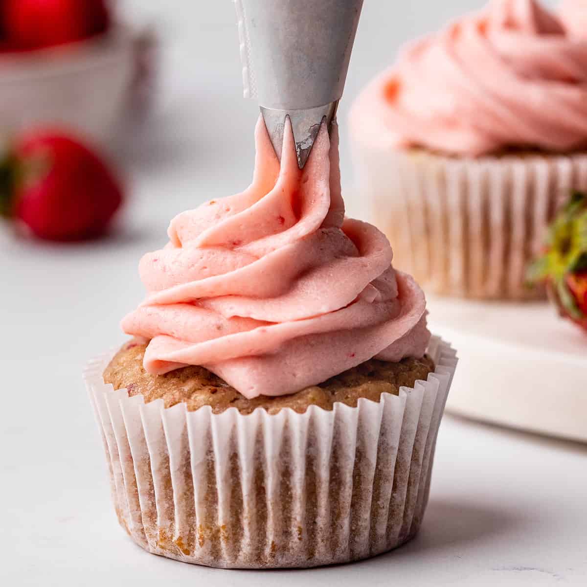Strawberry Buttercream Frosting being piped onto a cupcake