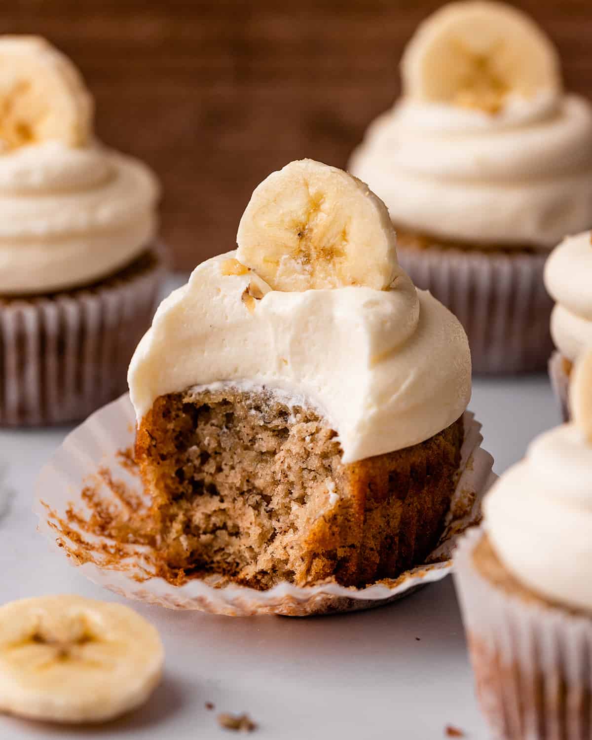 4 Banana Cupcakes with frosting, one with a bite taken out of it