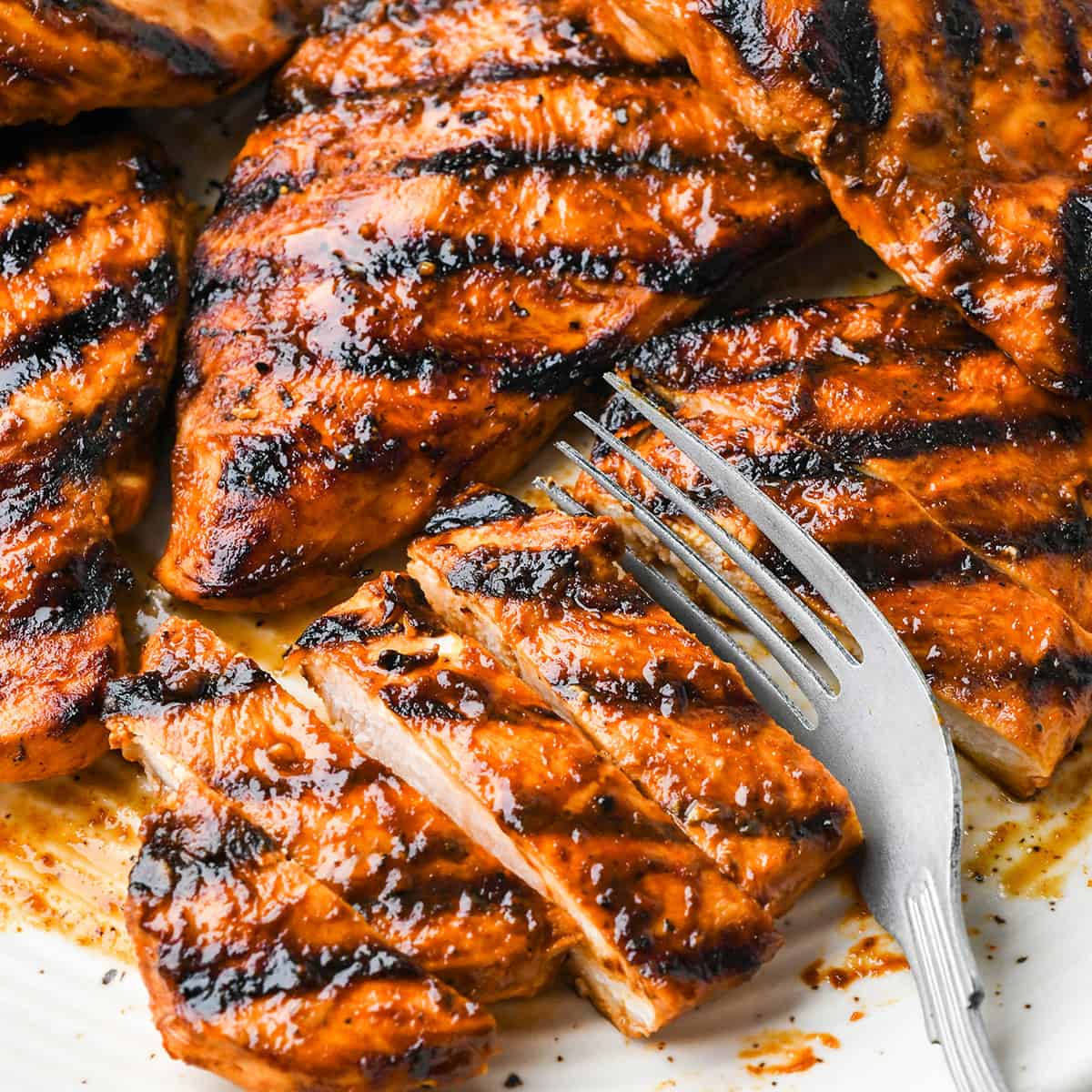 grilled BBQ Chicken breasts on a plate with a fork