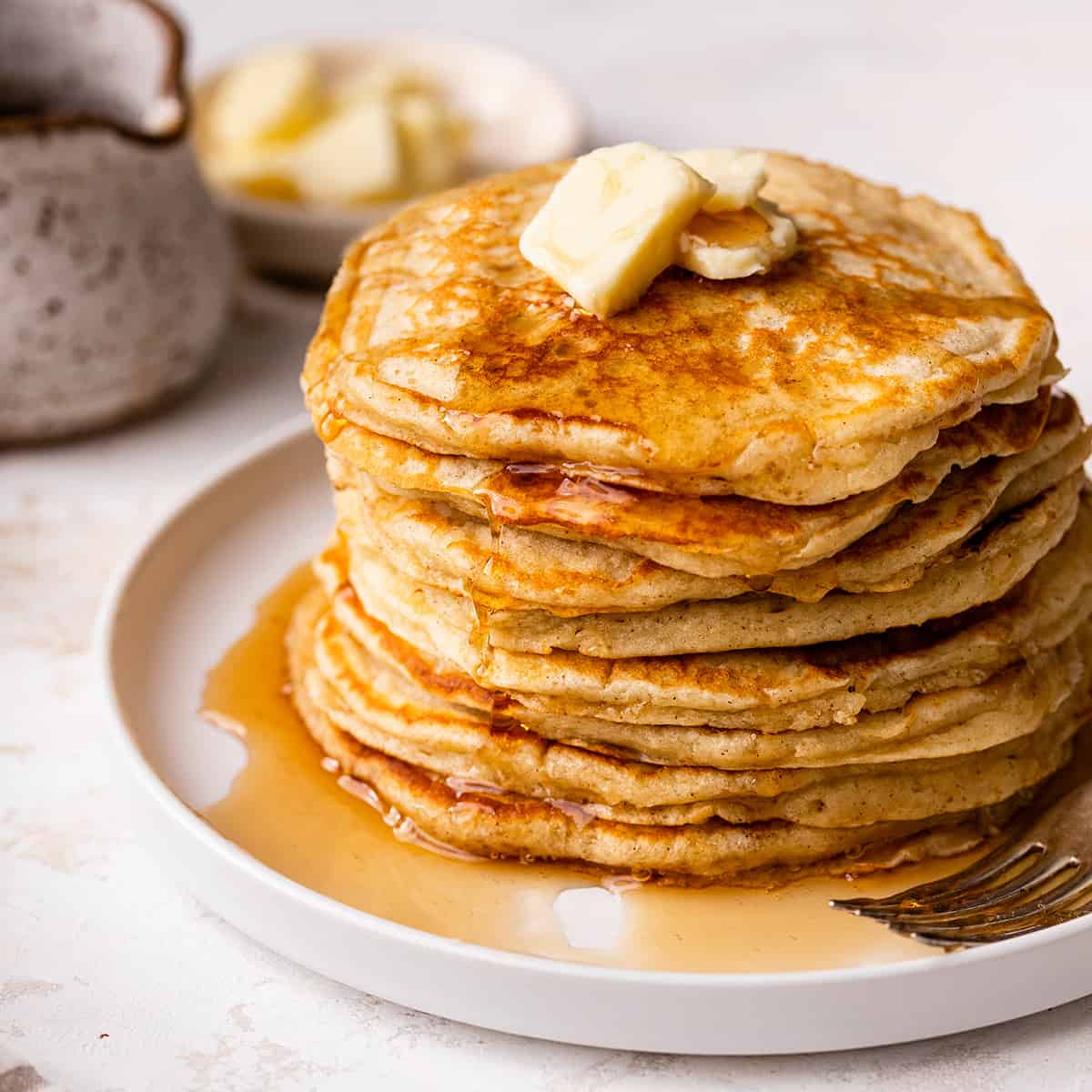 a stack of 8 Buttermilk Pancakes on a plate with butter and syrup on top