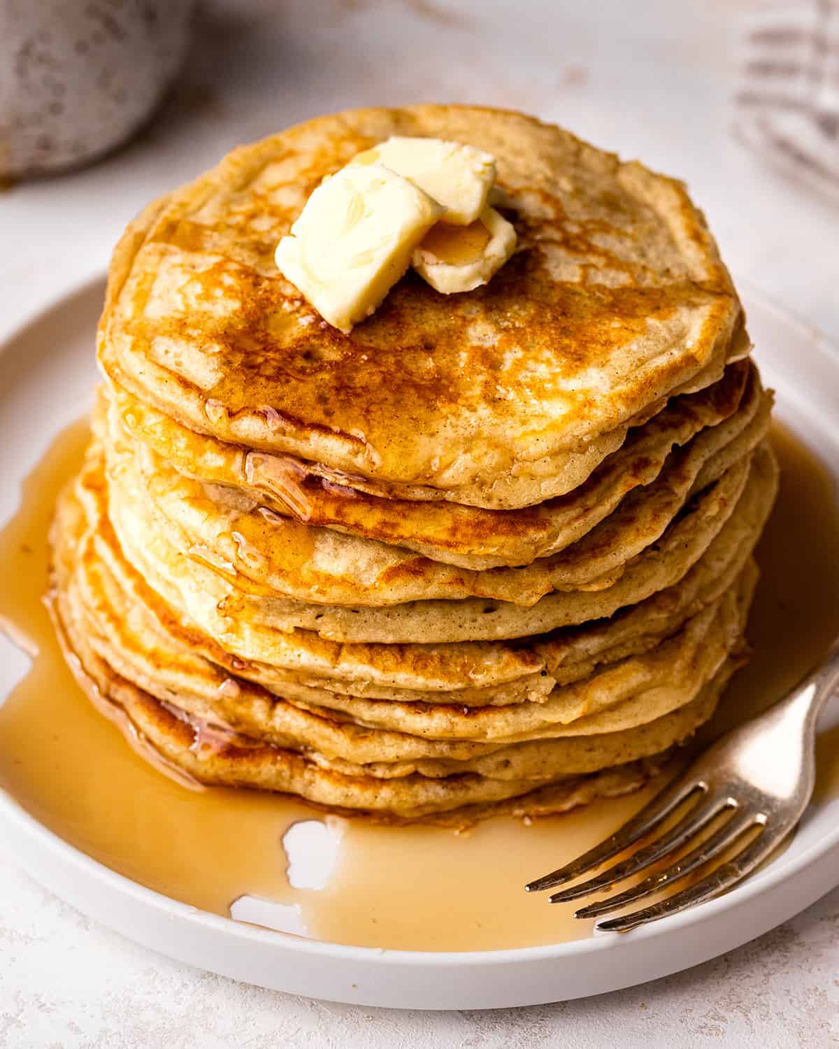a stack of 8 Buttermilk Pancakes on a plate with butter and syrup
