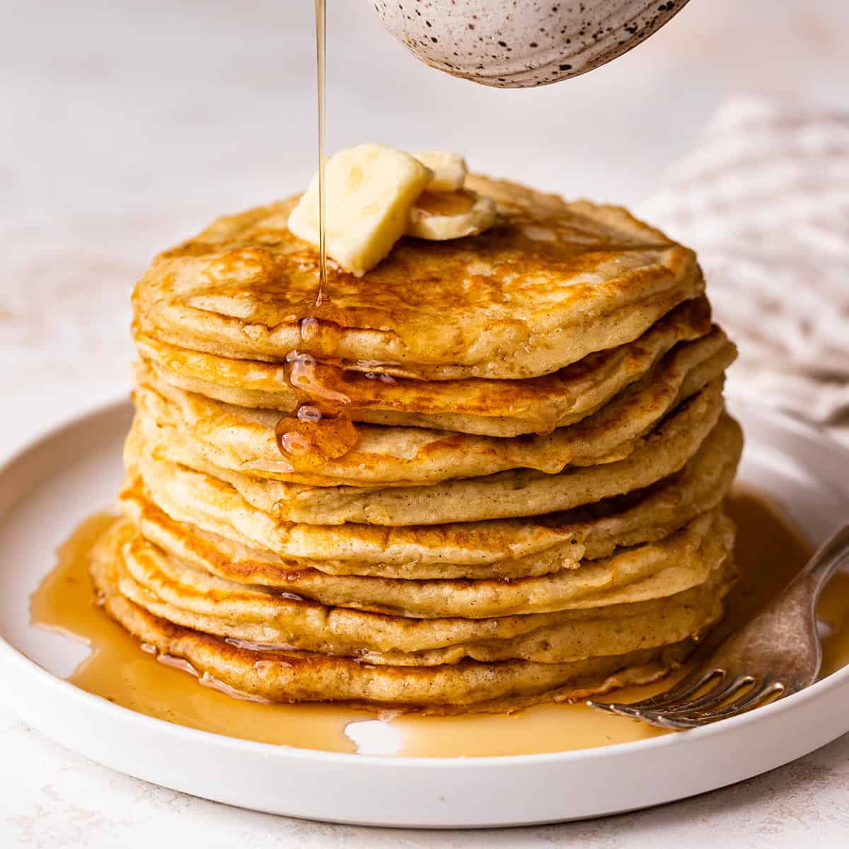 syrup being poured over a stack of 8 Buttermilk Pancakes