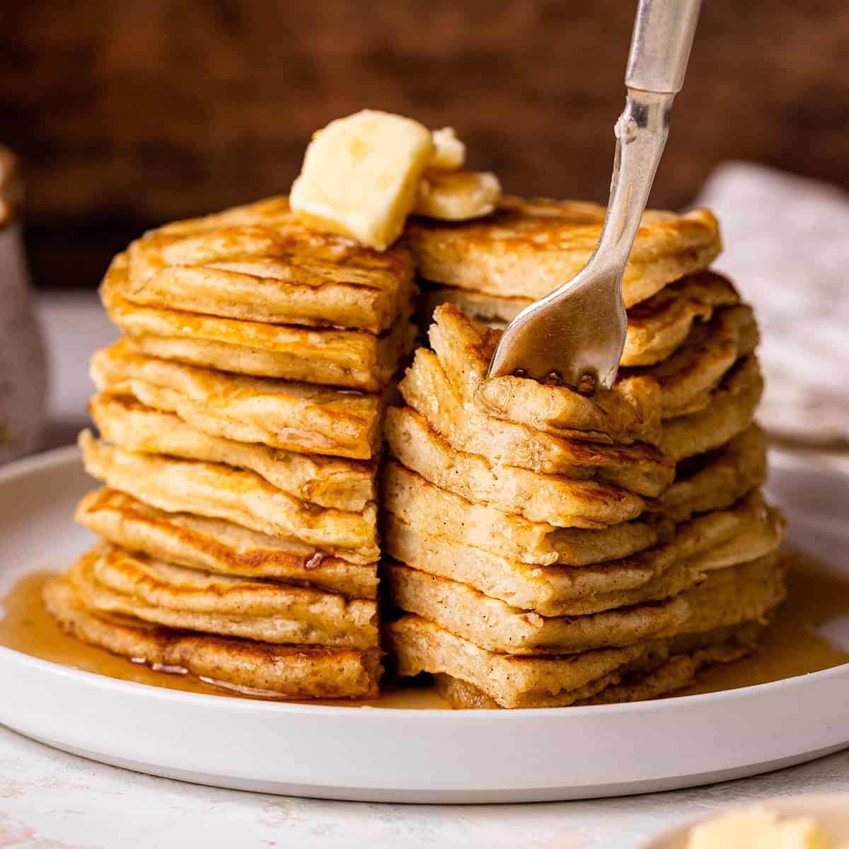a fork taking a bite out of a stack of 8 Buttermilk Pancakes