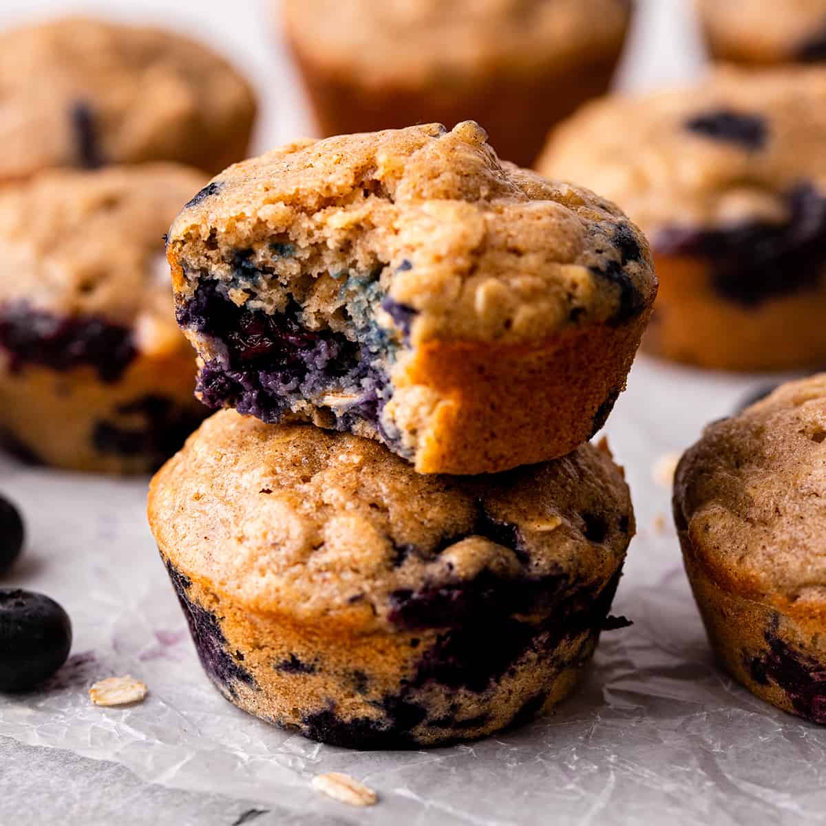 a stack of 2 Blueberry Oatmeal Muffins, the top one with a bite taken out of it
