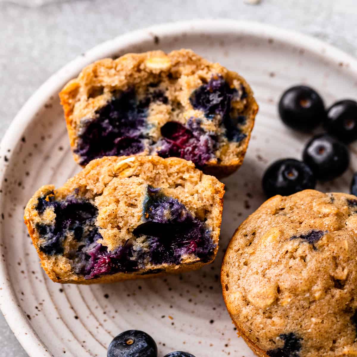 2 Blueberry Oatmeal Muffins on a plate, one cut in half 