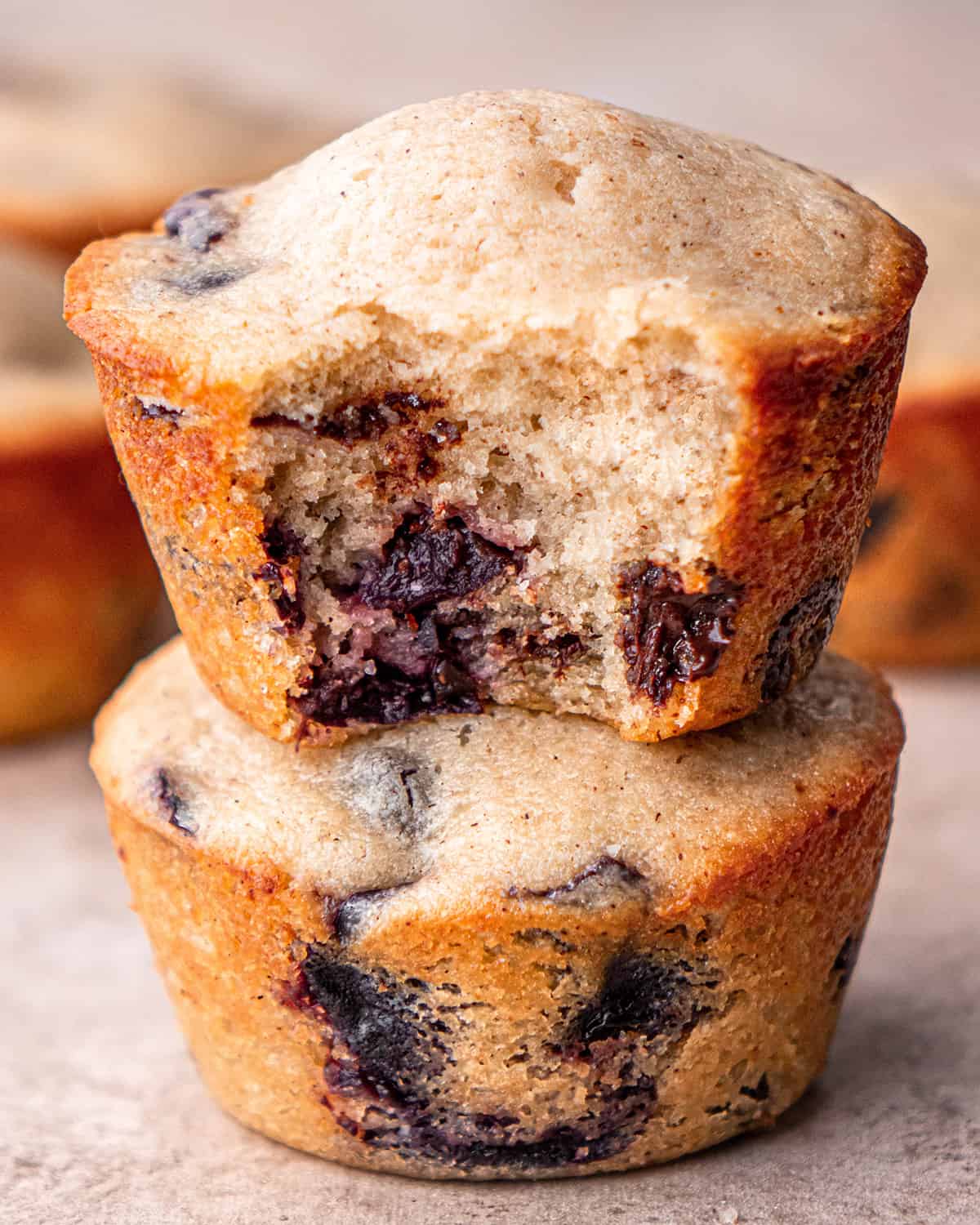 a stack of 2 Cherry Muffins, the top one with a bite taken out of it