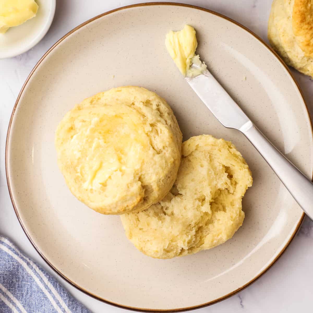 a homemade biscuit cut in half on a plate with butter