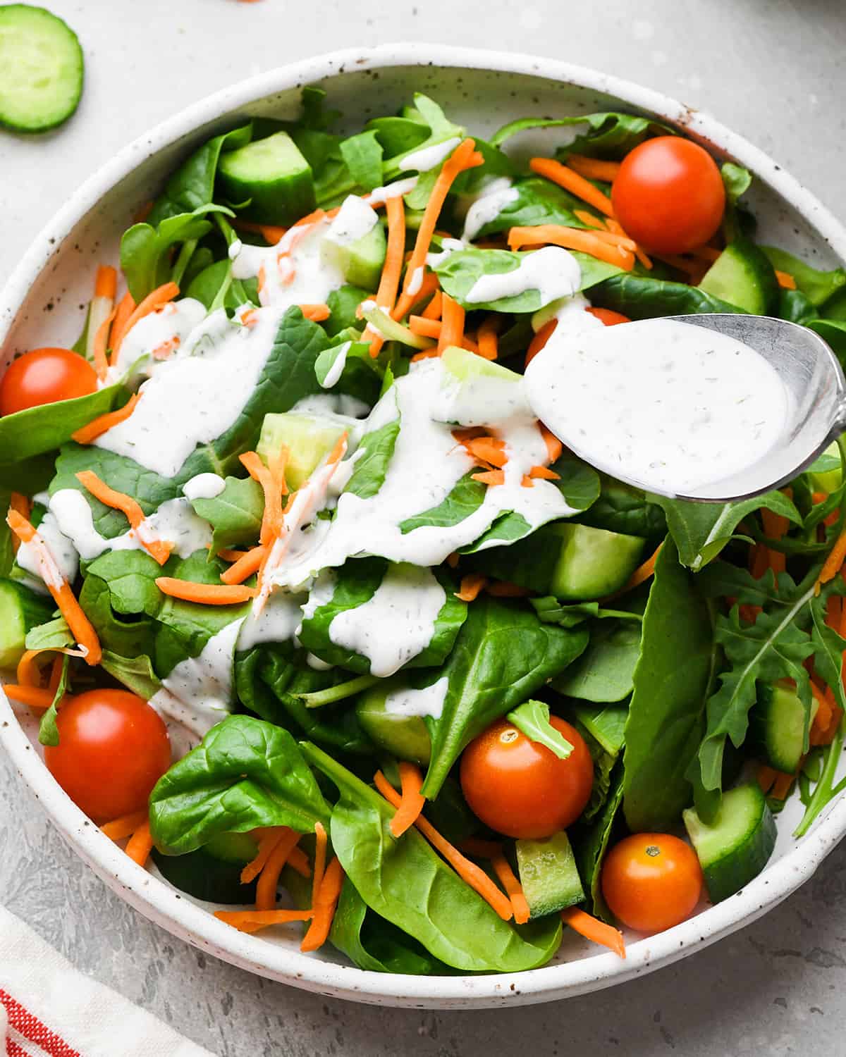 ranch dressing being drizzled on top of a salad