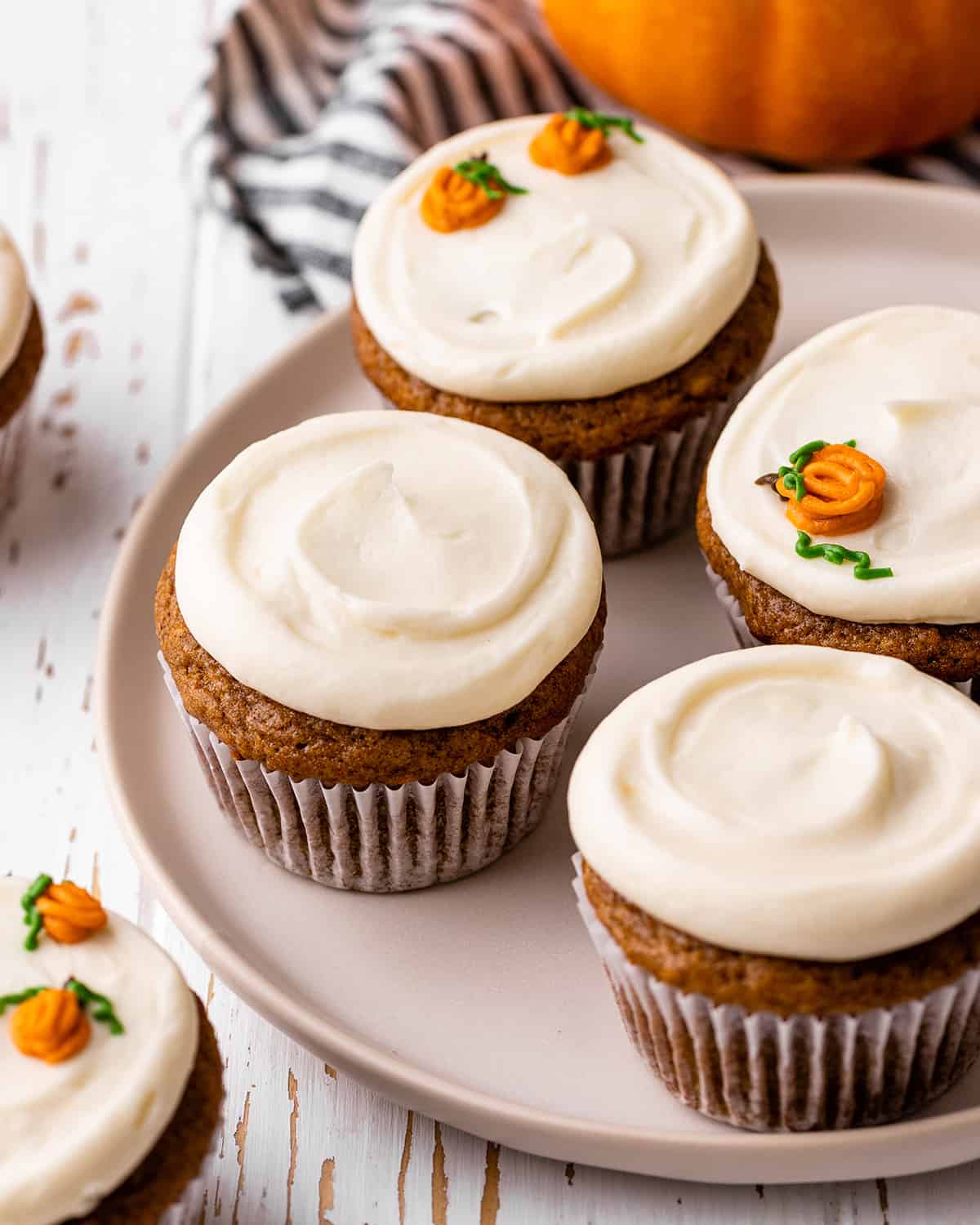 4 Pumpkin Cupcakes with cream cheese frosting on a plate